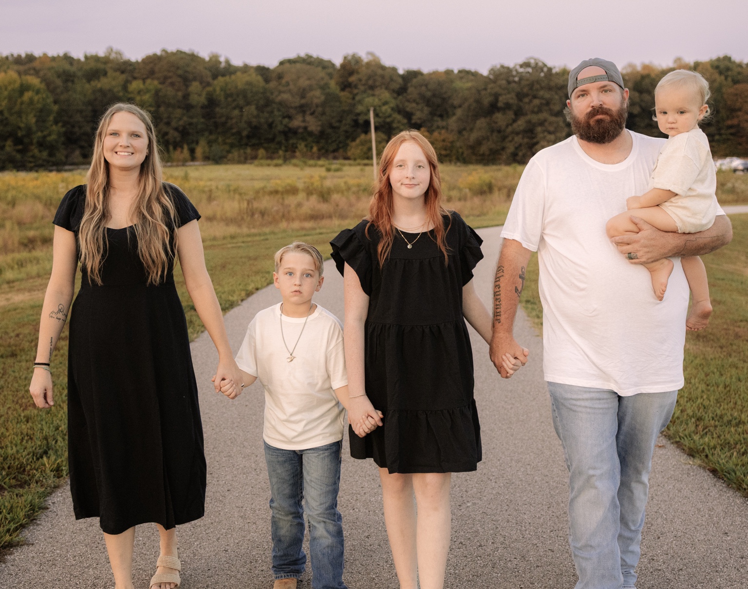 A family holding hands on a country road
